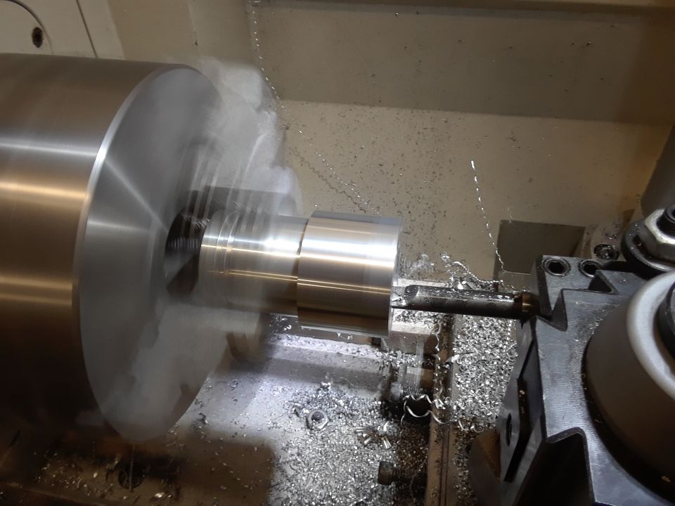Metal cylinder being shaped on a lathe with metal shavings flying