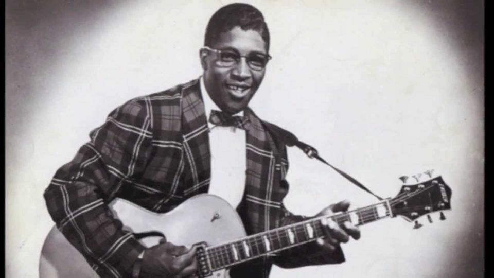 Man playing a guitar in a plaid suit