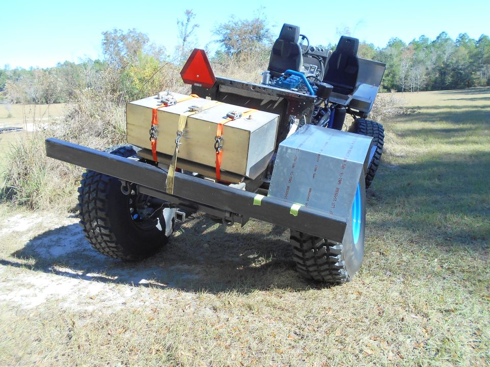 Custom off-road vehicle with large tires and cargo box, parked outdoors.