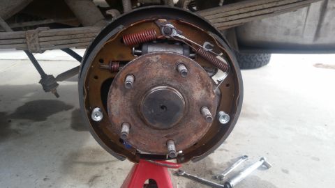 1985 Ford Bronco - A close-up view of the rear drum brake assembly of a 1985 Ford Bronco, showing the brake shoes, springs, and wheel cylinder. The vehicle is…