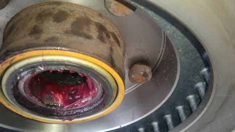 1985 Ford Bronco - A close-up view shows a greased wheel bearing assembly, likely from a 1985 Ford Bronco, with bright red grease packed inside the bearing an…