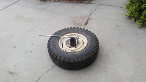 1985 Ford Bronco - A tire with a socket wrench attached to one of its lug nuts rests on a concrete surface. The tire is mounted on a rim and appears to be for…