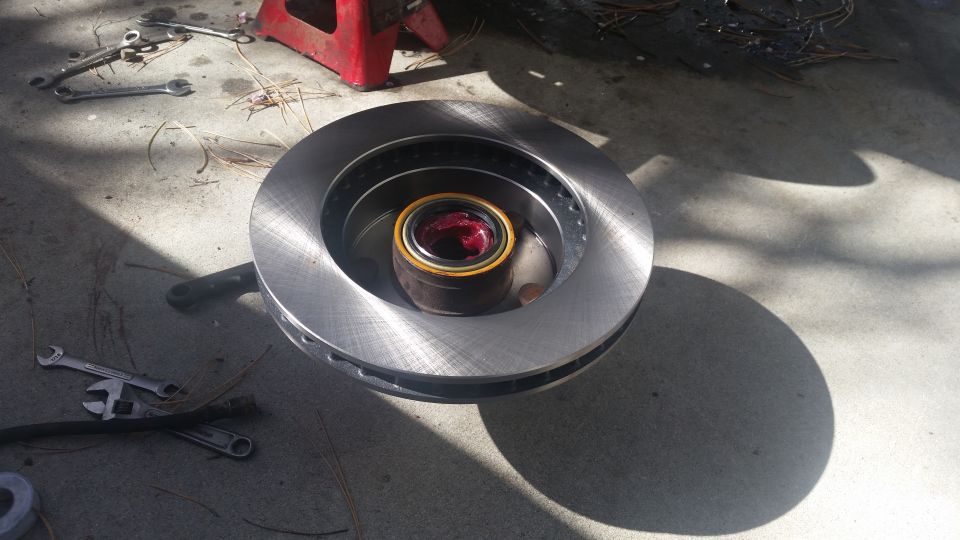 new brake rotor with bearing packed with red grease, tools on concrete