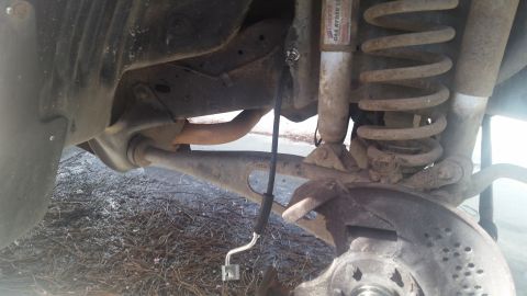 1985 Ford Bronco - Close-up view of vehicle suspension and brake components, showing a coil spring and shock absorber.