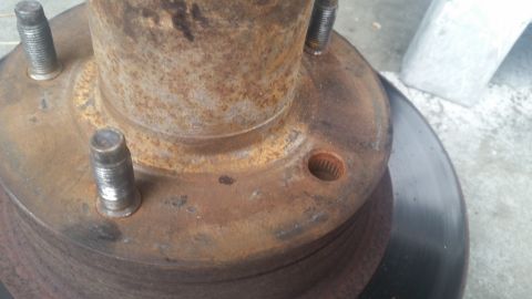 1985 Ford Bronco - Close-up of a heavily rusted wheel hub and brake rotor assembly.