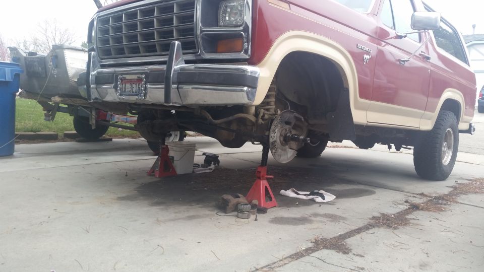 1980 Ford Bronco front end disassembled on jack stands, brake components removed