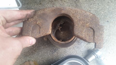 1985 Ford Bronco - A heavily rusted brake caliper is examined, revealing significant internal wear and debris.