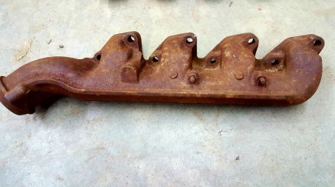 1973 Ford Mustang - A heavily rusted exhaust manifold is shown from the side, with visible bolt holes and a curved outlet pipe.