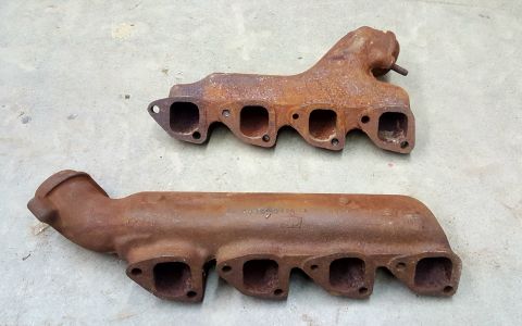 1973 Ford Mustang - A pair of old, rusty exhaust manifolds are shown resting on a concrete floor.