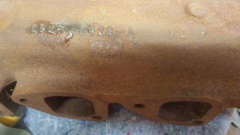 1973 Ford Mustang - A close-up view of a rusty exhaust manifold shows cast-in part numbers.