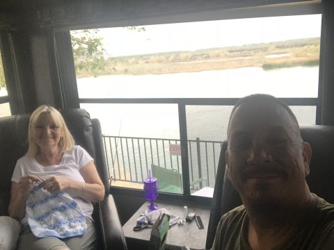 2018 Yugo GV - Couple relaxing inside an RV with a scenic view of a lake and surrounding landscape.