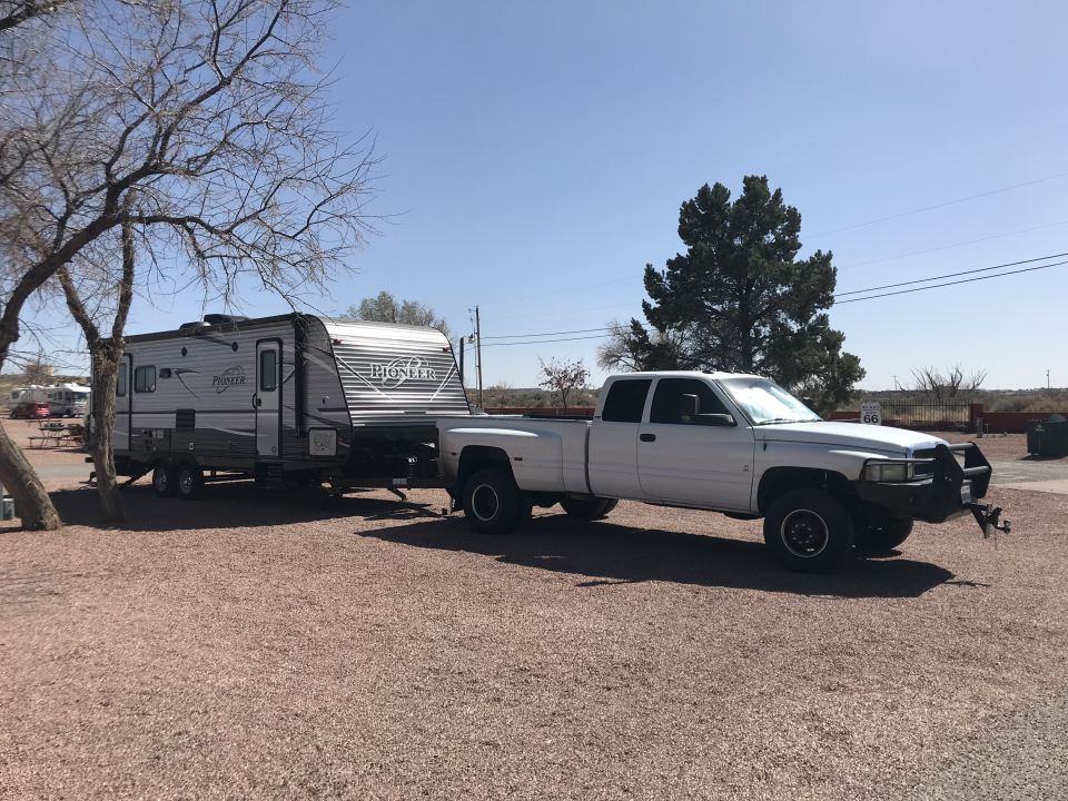 White dually pickup truck towing a Pioneer travel trailer