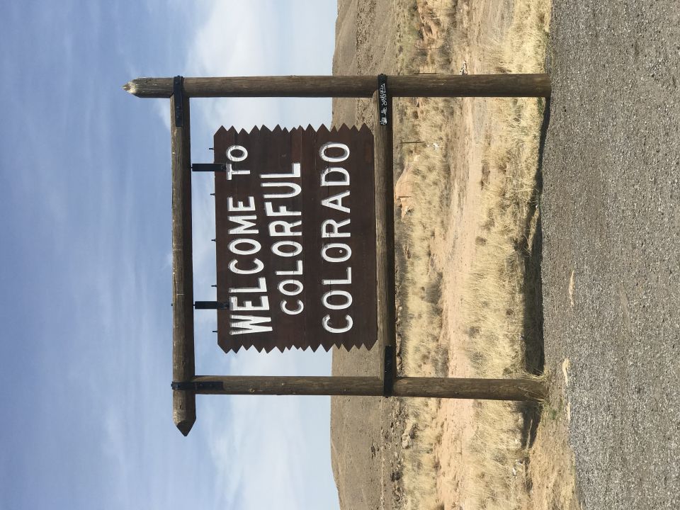 Welcome to Colorful Colorado sign on wooden posts next to a road