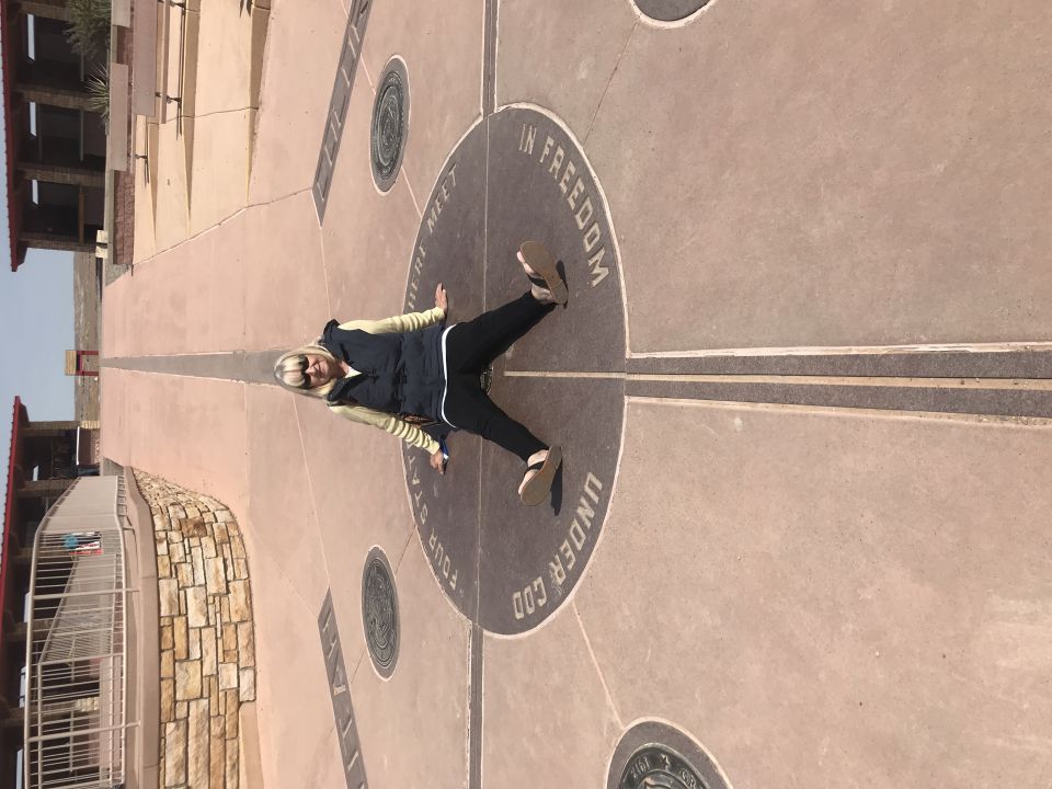 Woman lying on the Four Corners Monument marker