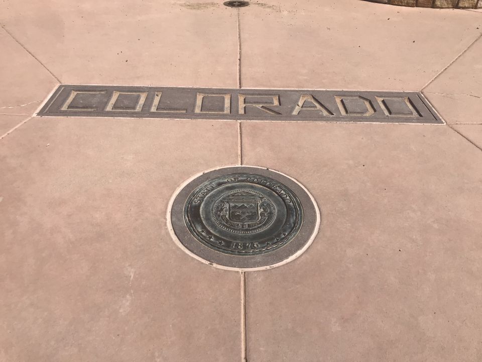 Colorado state line marker with state seal on sidewalk