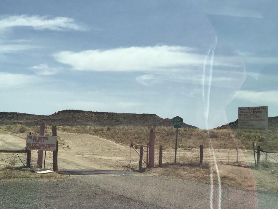 Dirt road entrance to a barren landscape with signs