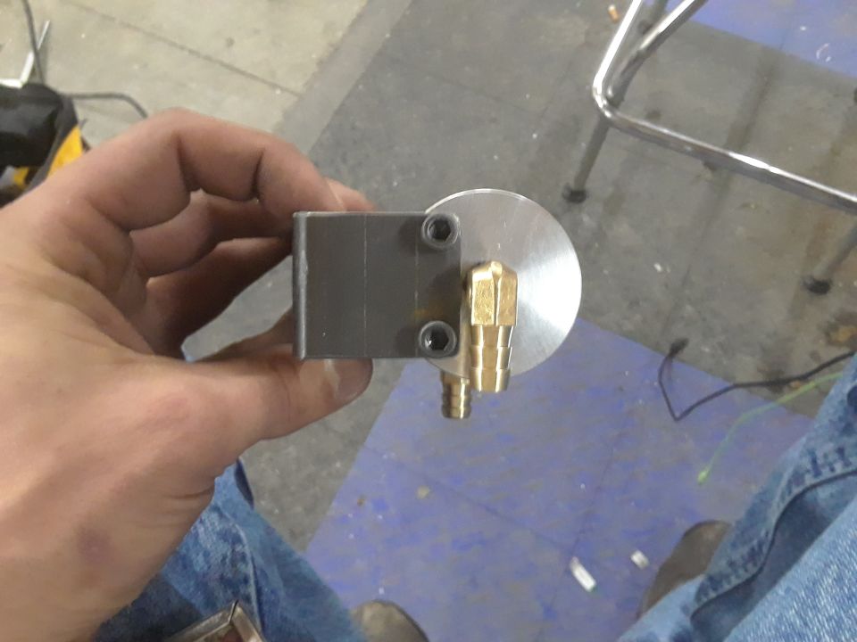 Close-up of a metal part with brass fittings held by a hand.