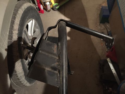 1967 Ford Custom Wagon - A close-up view shows a metal jack stand with a wingnut bolt extending from it, positioned next to a tire. The jack stand appears to be mad…