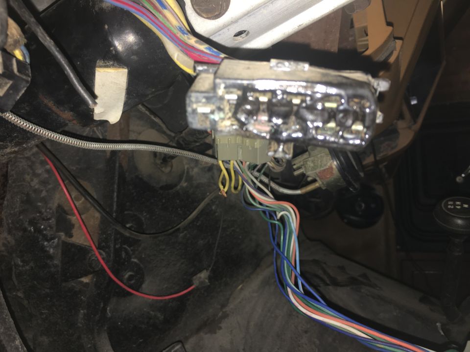 Exposed fuse box and colorful wiring harness behind a vehicle dashboard