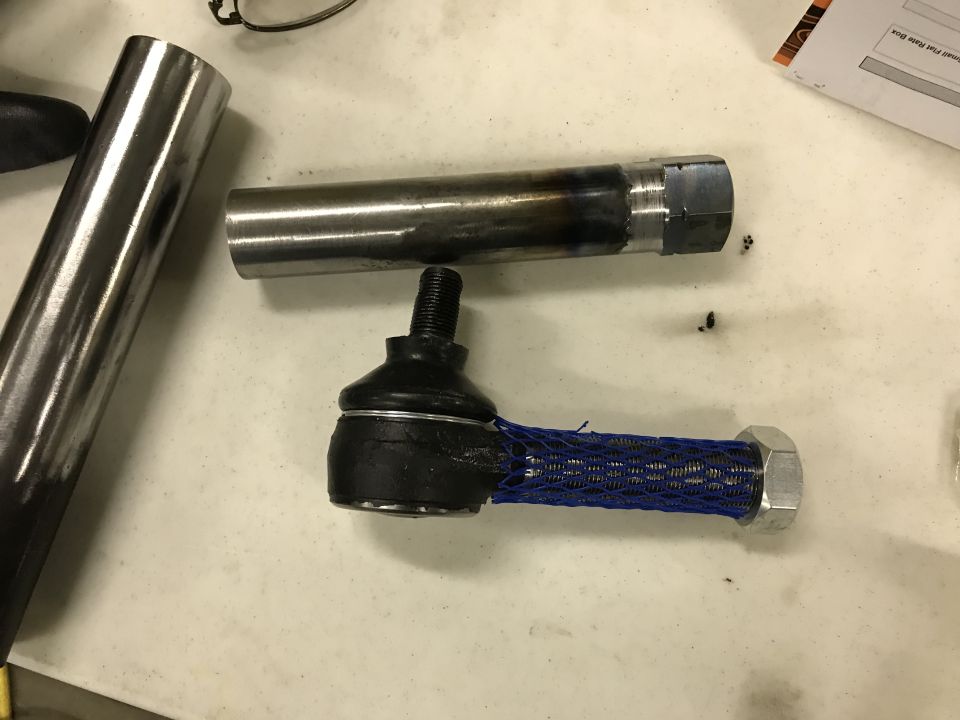 Tie rod end with blue protective net and metal tube with hex nut.