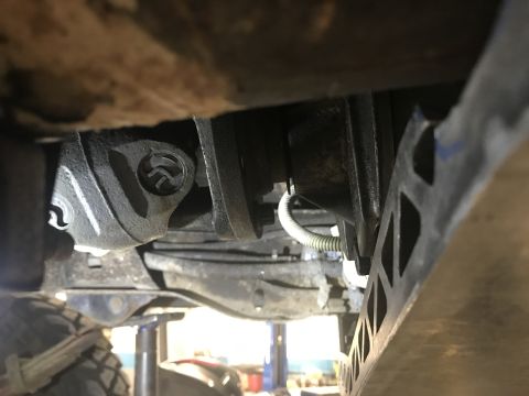 1995 Ford Bronco - A low-angle shot looking up at the underside of a vehicle, focusing on the drivetrain components like a driveshaft support bearing and part…