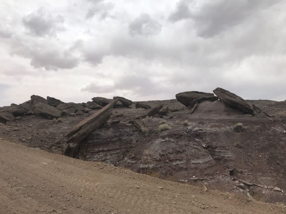 Rocky terrain with a dirt path and large boulders under a cloudy sky.
