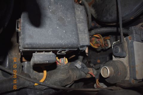 1996 Ford Bronco - A close-up view shows a black plastic fuse box with a Ford logo, connected to a bundle of colorful wires and various electrical connectors.…