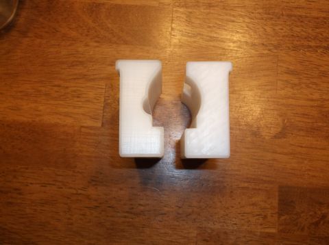 1995 Mercury Grand Marquis - Two white 3D printed parts are shown on a wooden surface. The parts appear to be designed to hold a cylindrical object.