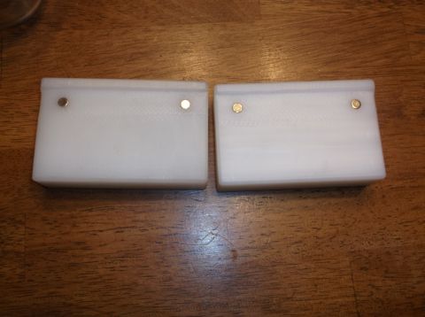 1995 Mercury Grand Marquis - Two white rectangular objects with two brass pins each are placed on a wooden surface.