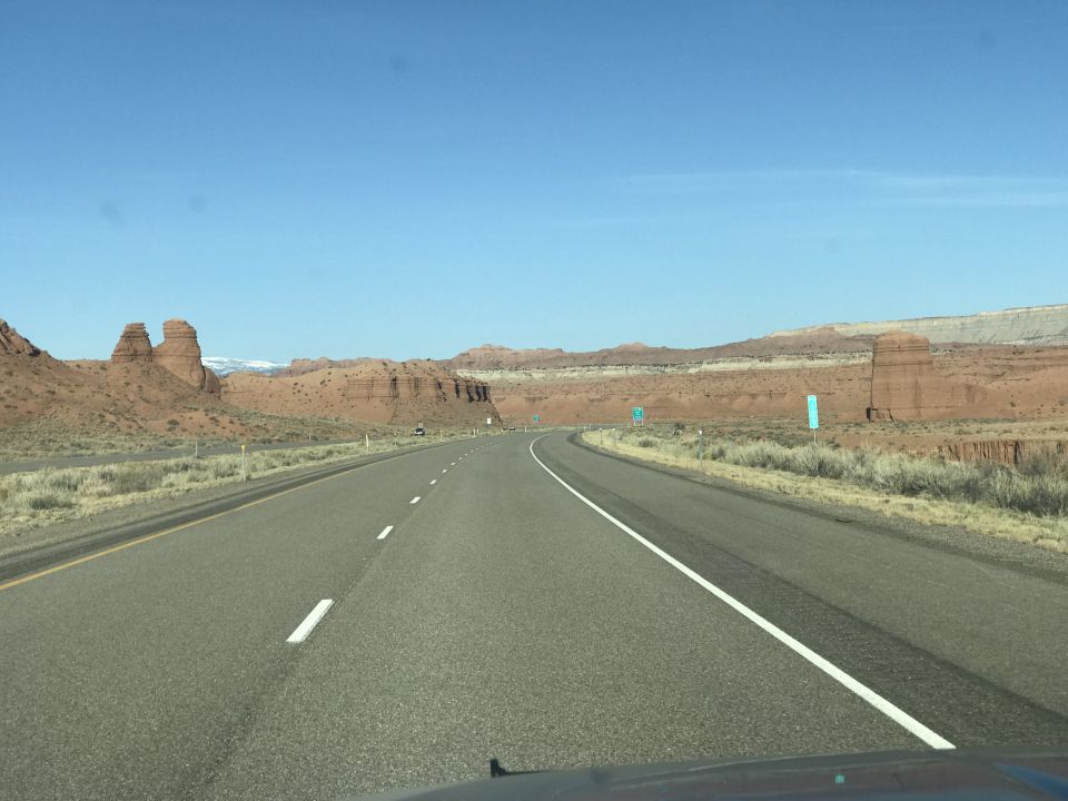 Highway through a desert landscape with red rock formations.