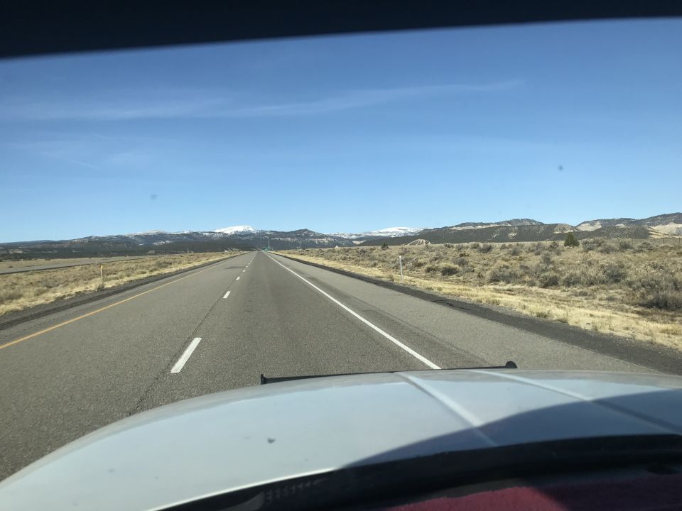 View from inside a vehicle on a highway towards mountains.