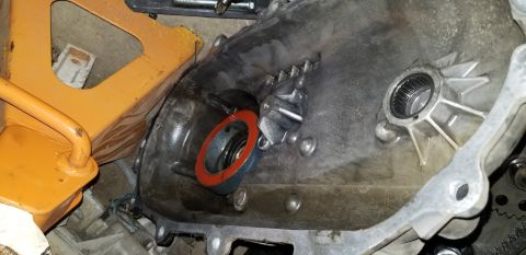 1995 Ford Bronco - A close-up view shows a transmission housing with a red gasket and a bearing installed. An orange jack is visible in the background, sugges…