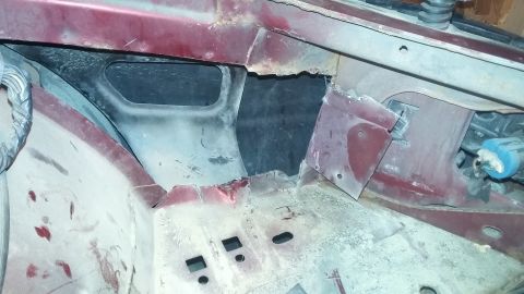 2000 Pontiac Grand Prix - This is a close-up view of the rusted and cut metal structure of a vehicle's engine bay or fender well area. The red exterior paint is visi…