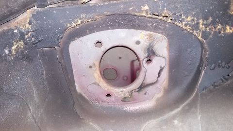 2000 Pontiac Grand Prix - This is a close-up view of the underside of a vehicle's suspension mounting point, showing rust and wear around the shock tower opening.