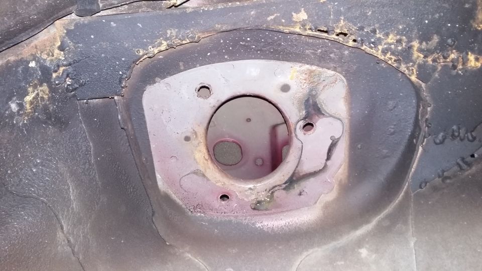 Underside of a vehicle's shock tower opening with rust and wear.