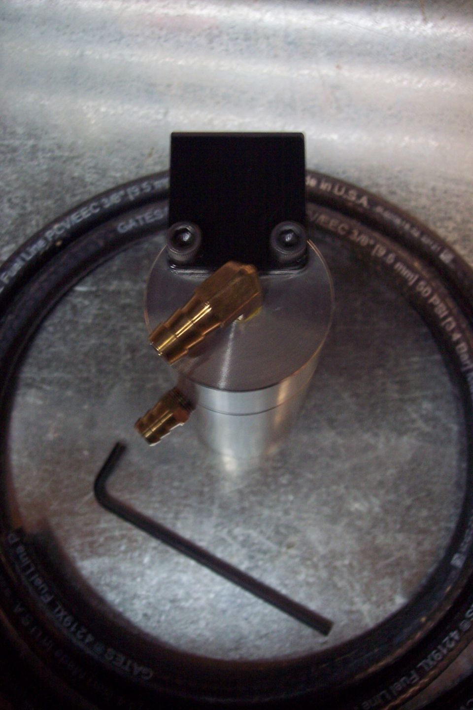 Black oil catch can with brass fittings and a Gates fuel line hose.