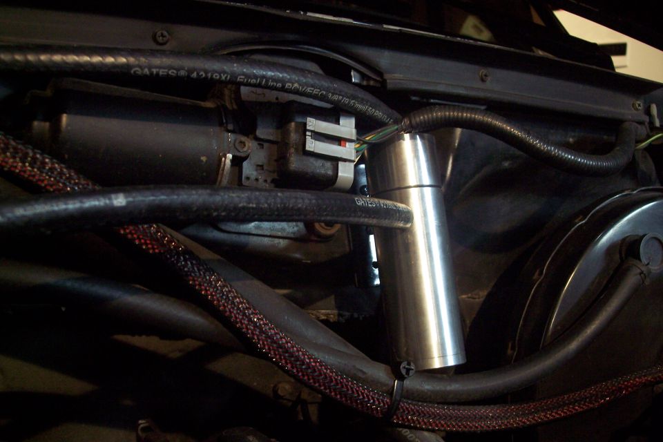 Engine bay with hoses, wiring, and a silver reservoir. Text on hose: GATES® 4510X1 Fuel Line.