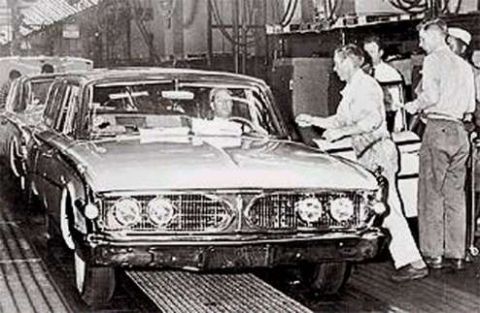 1967 Ford Custom Wagon - A black and white photograph showing a line of cars on an assembly line, with workers attending to them. The front of a sedan is prominentl…
