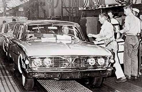 Cars on an assembly line, with a focus on the front of a sedan.