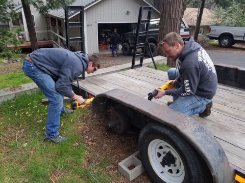 1968 Ford Bronco - Two men are working on a trailer, with one using a reciprocating saw to cut a metal fender. Sparks are flying from the cutting action.