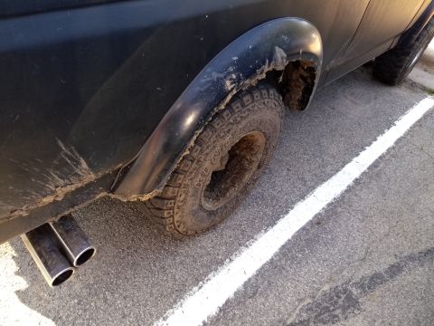 1996 Ford Bronco - Close-up of a dirty vehicle's rear wheel and exhaust pipes, with mud splattered on the body.