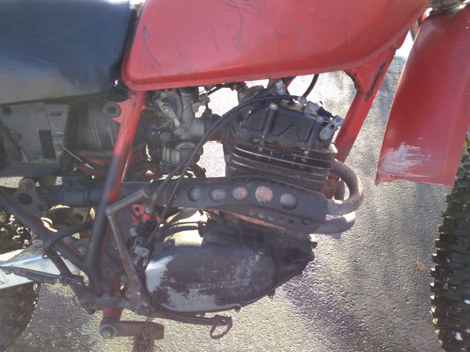 Red dirt bike engine and frame, side view.