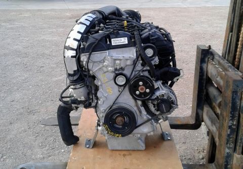 1995 Peterbilt 379 - A close-up view of a vehicle engine, mounted on a pallet and supported by a forklift.