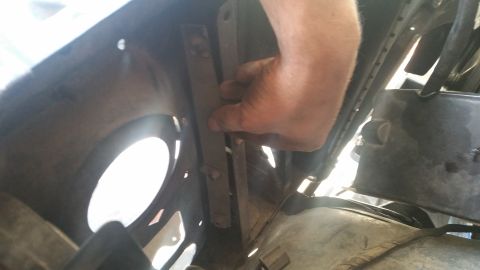 1985 Ford Bronco - Close-up of a hand interacting with a metal bracket, likely during a repair or adjustment.