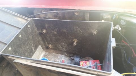 1985 Ford Bronco - A plastic toolbox is mounted in the engine bay of a vehicle, containing various items.