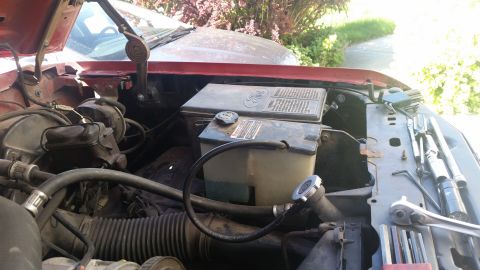 1985 Ford Bronco - The engine bay of a vehicle, showing various components and tools ready for maintenance.