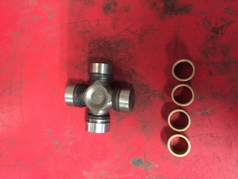 1984 Ford Bronco - A universal joint and four bearing races are laid out on a red, textured surface.