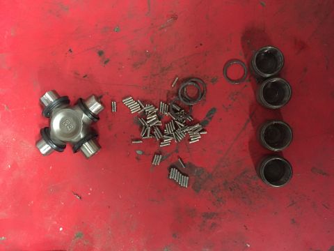 1984 Ford Bronco - Disassembled universal joint components laid out on a red workbench surface.