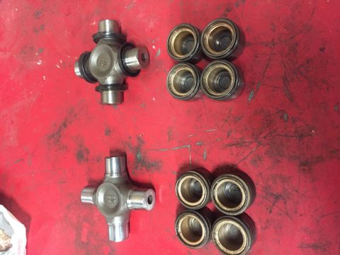 1984 Ford Bronco - A pair of universal joints and a set of bearings are displayed on a red workbench.
