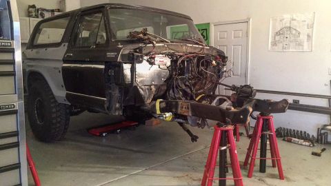 1979 Ford Bronco - A 1979 Ford Bronco is undergoing restoration in a garage, with its front end disassembled and the chassis supported by jack stands. The veh…